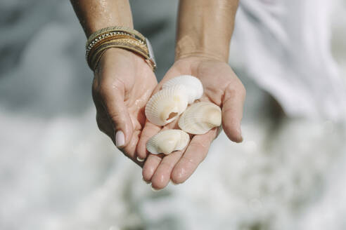 Frau hält Muscheln in der Hand am Strand - SIF00971