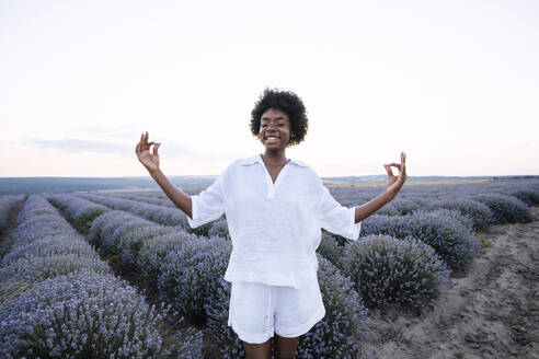 Lächelnde Frau meditiert in einem Lavendelfeld - AAZF01137