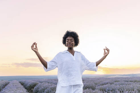 Junge Frau mit geschlossenen Augen meditiert in einem Lavendelfeld - AAZF01139