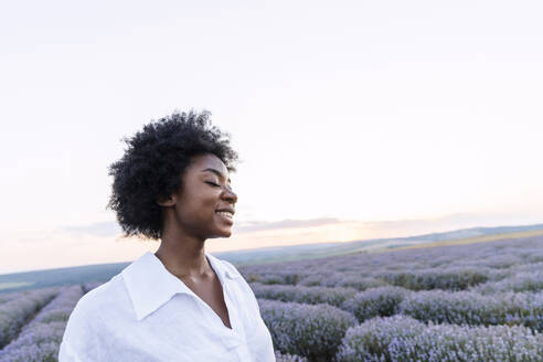 Smiling woman in lavender field under sky - AAZF01142