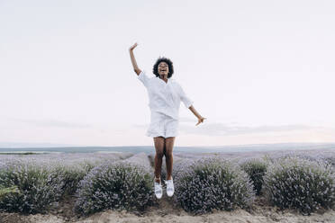 Happy woman jumping near lavender field - AAZF01147