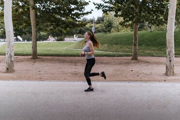 Redhead woman jogging on footpath at park - PBTF00260