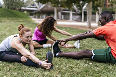 Multi-ethnic friends stretching and doing yoga in park - PBTF00272