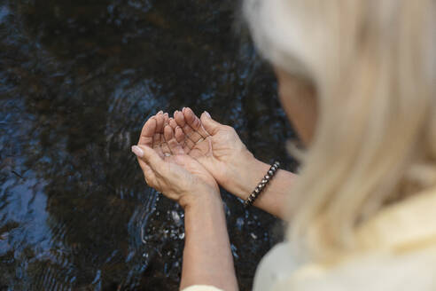 Woman with water in cupped hands - LLUF01076