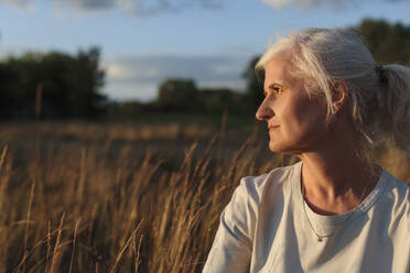 Reife Frau mit grauem Haar bei Sonnenuntergang - LLUF01095