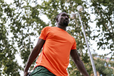 Mann mit orangefarbenem T-Shirt trainiert im Park - PBTF00308
