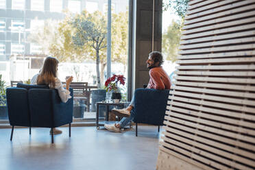 Business colleagues sitting on chairs in office lobby - JOSEF21046