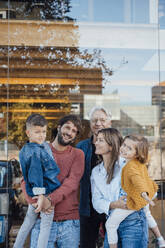 Family standing together in front of glass wall - JOSEF21062