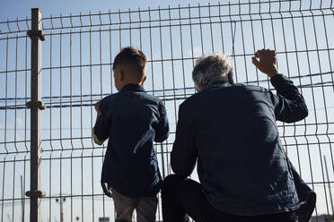 Enkel und Großvater schauen durch den Zaun - JOSEF21077