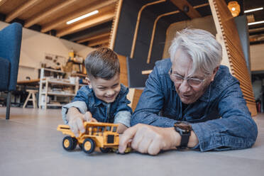 Junge und älterer Mann spielen mit Spielzeugautos zu Hause - JOSEF21109