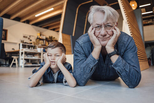 Senior man and boy leaning on elbows lying down at home - JOSEF21111