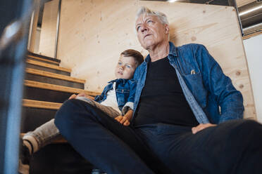 Grandson and grandfather sitting on staircase at home - JOSEF21115