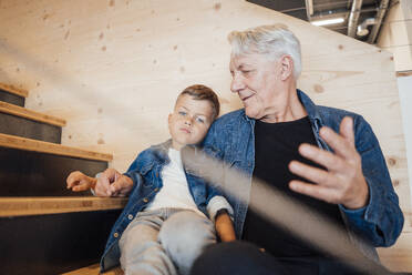 Grandson and grandfather sitting together at home - JOSEF21116