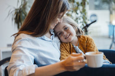 Smiling daughter sitting with mother having coffee at home - JOSEF21122