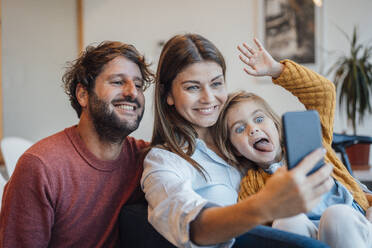 Happy family taking selfie through smart phone sitting at home - JOSEF21127