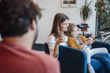 Tochter benutzt Smartphone mit Mutter beim Kaffee trinken zu Hause - JOSEF21128