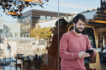 Man using smart phone near glass wall - JOSEF21139