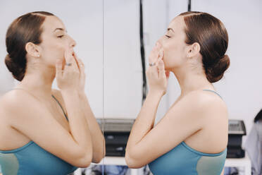 Ballet dancer applying face cream looking in mirror - MRRF02696