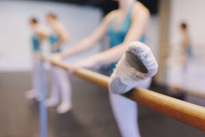 Dancer wearing ballet shoe doing stretching in dance school - MRRF02699