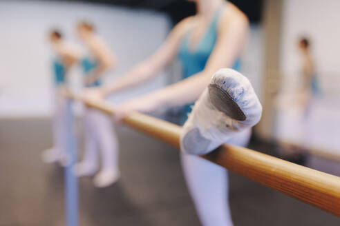 Dancer wearing ballet shoe doing stretching in dance school - MRRF02699