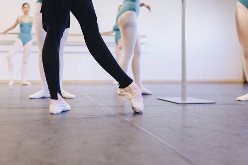 Ballettlehrer mit Ballettschuhen unterrichtet Schüler in einer Tanzschule - MRRF02712