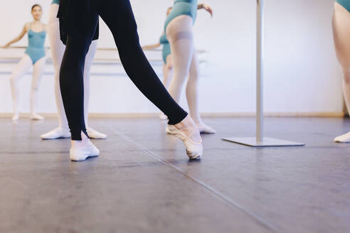 Instructor wearing ballet shoes teaching students in dance school - MRRF02712