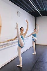 Tänzerinnen und Tänzer üben Ballett auf einem Bein stehend in einer Tanzschule - MRRF02721