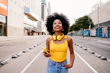 Beautiful young happy african woman with afro curly hairstyle strolling in the city - Cheerful black student walking on the streets - DMDF05972