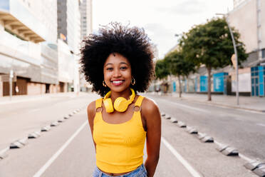 Fröhliche schwarze Studentin mit Afro-Lockenfrisur genießt einen Stadtspaziergang - junge afrikanische Frau strahlt Glück aus - DMDF05973