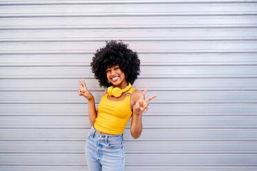 Beautiful young happy african woman with afro curly hairstyle strolling in the city - Cheerful black student portrait on colorful wall background - DMDF05982