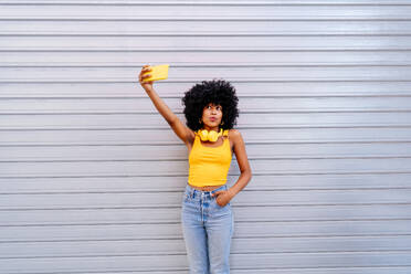 Beautiful young happy african woman with afro curly hairstyle strolling in the city - Cheerful black student portrait on colorful wall background - DMDF05988