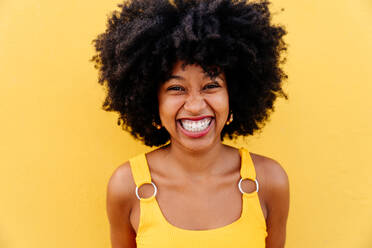 Beautiful young happy african woman with afro curly hairstyle strolling in the city - Cheerful black student portrait on colorful wall background - DMDF05989