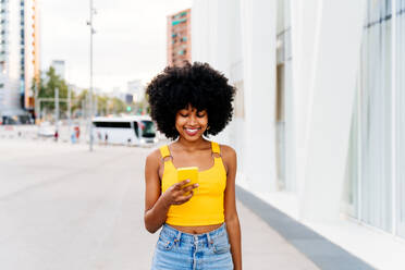 Beautiful young happy african woman with afro curly hairstyle strolling in the city - Cheerful black student girl walking on the street - DMDF06026