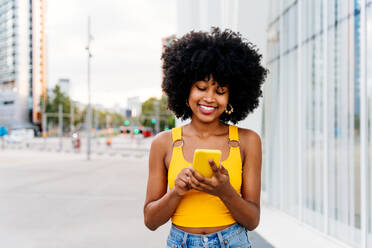 Beautiful young happy african woman with afro curly hairstyle strolling in the city - Cheerful black student girl walking on the street - DMDF06029