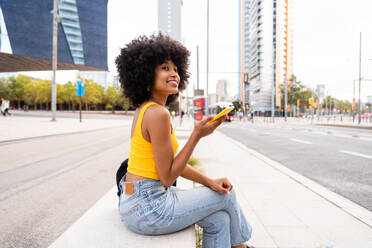 Junge afrikanische Frau mit Afro-Lockenfrisur genießt einen Spaziergang durch die Stadt - glückliches Studentenmädchen in Bewegung - DMDF06031