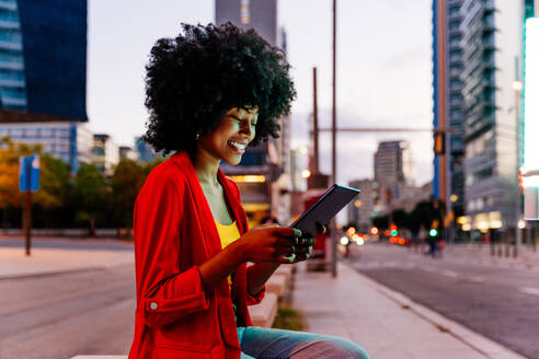 Junge afrikanische Frau mit Afro-Lockenfrisur genießt abendlichen Spaziergang in der Stadt - glückliches schwarzes Studentenmädchen unterwegs - DMDF06045