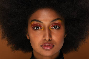 Porträt einer attraktiven Afroamerikanerin bei einer Beauty-Session im Studio - Schöne Frau posiert vor farbenfrohem Hintergrund - DMDF06123