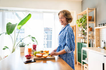 Beautiful mature senior woman at home, domestic life and leisure moments - 50-60 years old pretty female adult cooking healthy food at home in the kitchen for diet - DMDF06245