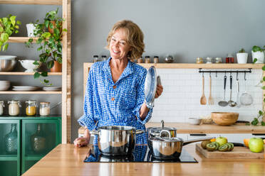 Eine schöne ältere Frau genießt ihr häusliches Leben und ihre Freizeitmomente zu Hause, indem sie Mittagessen in der Küche kocht - im Alter von 50-60 Jahren - DMDF06263