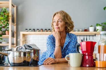 Porträt einer attraktiven, reifen Frau im häuslichen Umfeld - Genießen des Frühstücks in der Küche, im Alter von 50-60 Jahren - DMDF06270