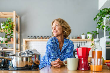 Beautiful mature senior woman at home, domestic life and leisure moments - 50-60 years old pretty female adult portrait in the kitchen at breakfast - DMDF06271