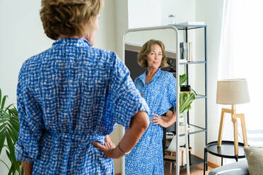 Eine schöne ältere Frau genießt ihr häusliches Leben und betrachtet sich selbst im Spiegel - im Alter von 50-60 Jahren - DMDF06301