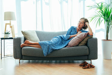 Entspannte ältere Frau genießt ihr Zuhause und Freizeitmomente - hübsche 50-60-jährige auf dem Sofa - DMDF06306