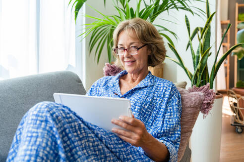 Entspannte ältere Frau genießt ihr Zuhause und Freizeitmomente - attraktive 50-60-jährige auf dem Sofa - DMDF06312