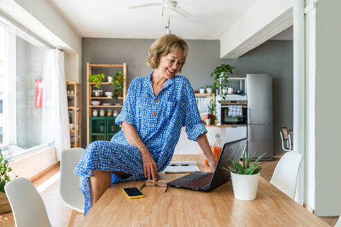 Attraktive ältere Frau genießt ihr Zuhause und Freizeit - im Alter von 50-60 Jahren arbeitet sie remote mit ihrem Laptop - DMDF06325