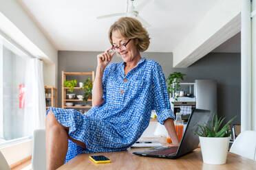 Beautiful mature senior woman at home, domestic life and leisure moments - 50-60 years old pretty female adult remote working with computer laptop - DMDF06331