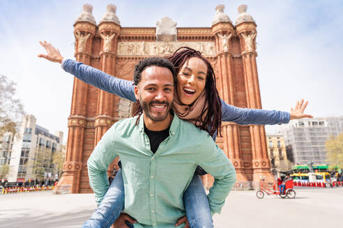 Schönes glückliches hispanisches Latino-Liebespaar, das sich im Freien trifft - Touristen in Barcelona, die sich während der Sommerferien amüsieren und das historische Wahrzeichen Arc de Triumf besuchen - DMDF06379