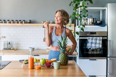 Sportliche ältere Frau genießt gesunde Mahlzeit nach dem Training zu Hause - aktives und gesundes Leben im Alter - DMDF06403