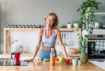 Beautiful mature senior woman at home, domestic life and leisure moments - 50-60 years old pretty female adult wearing sportswear eating healthy food after fitness workout - DMDF06406