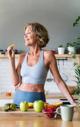 Beautiful mature senior woman at home, domestic life and leisure moments - 50-60 years old pretty female adult wearing sportswear eating healthy food after fitness workout - DMDF06409